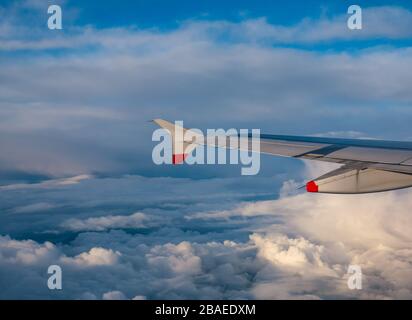 British Airways Airbus A319 Flugzeugflügel durch Flugzeugfenster über Wolkenformationen am sonnigen Tag des Inlandsflugs, Großbritannien Stockfoto