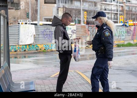 Saloniki, Griechenland - 23. März 2020: Ein Polizeibeamter überprüft die Dokumente eines Bürgers, da das Land die Verbreitung des COVID nicht unter Kontrolle hat Stockfoto