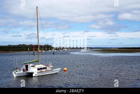 Weißes, glattes Boot, das am bewölkten Tag auf Wasser festgemacht wurde Stockfoto