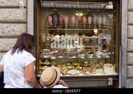 Florenz, Italien - 13. August 2019: Mutter und Kind bewundern die Schaufensterauslage im Bonbons- und Süßwarenladen Migone in Florenz Stockfoto