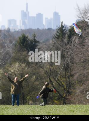 27. März 2020, Hessen, Frankfurt am Main: Devin und seine Mutter Antonia fliegen auf dem Lohrberg in Frankfurt einen Drachen. Im Hintergrund sieht man die Skyline der Stadt. Foto: Arne Dedert / dpa Stockfoto