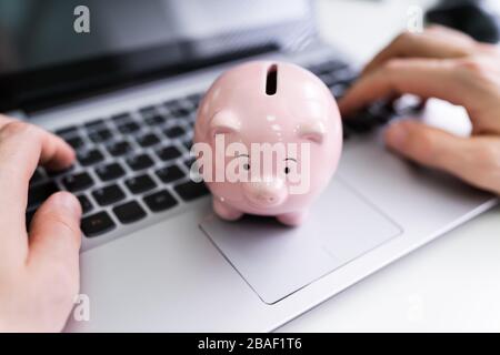 Nahaufnahme der Geschäftsmann Hand Arbeiten am Laptop mit rosa Sparschwein Stockfoto