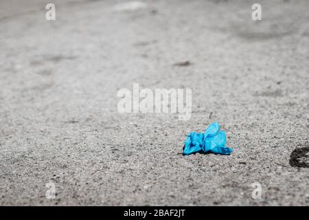 Ein gebrauchte blaue Handschuh wird auf dem Boden in der Straße platziert, um sich vor dem Corona-Virus zu schützen Stockfoto