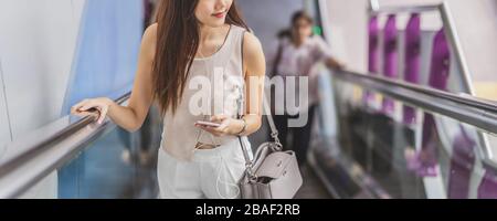 Banner, Webseite oder Deckblatt von Passagieren asiatischer Frauen mit Smartphone und Rolltreppe in der U-Bahn-Station, wenn sie in großen Reisen sind Stockfoto