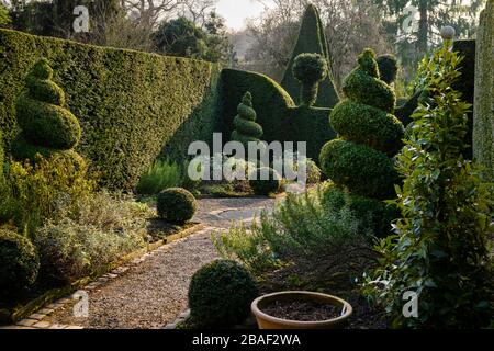 Country Cottage Kräutergarten (dekorative dekorative dekorative beschnittene Evergreens, topiäre Spiralen & Bälle, Kräuter, Schotterpfad) - York Gate Garden, Leeds UK. Stockfoto