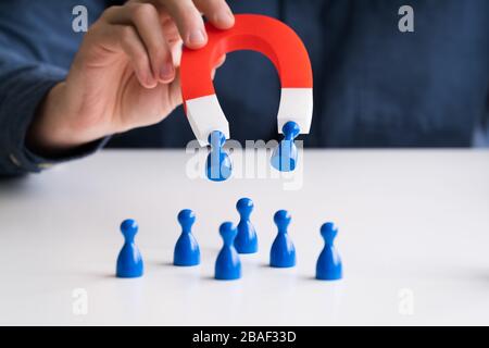 Der Geschäftsmann Hand zieht Blau menschliche Figuren in einer Reihe stehen mit Hufeisen Magnet Stockfoto