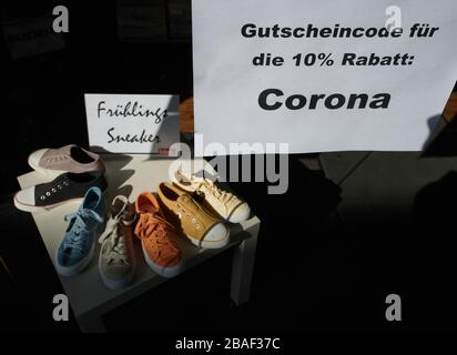 München, Deutschland. März 2020. Ein Schuhhändler hat den Gutschein-Code "Corona" für einen 10-prozentigen Rabatt für seinen Online-Shop in seinem Schaufenster aufgehängt. Zur Eindämmung des Corona-Virus hat NRW alle Ansammlungen von drei oder mehr Menschen in der Öffentlichkeit verboten. Credit: Bernd Thissen / dpa / Alamy Live News Stockfoto