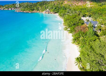 Panoramablick auf die Bucht von Anse Petite mit weißem Sand, türkisfarbenem Meer, blauem Ozean und üppiger bewaldeter Landzunge, Mahe, Seychellen Stockfoto