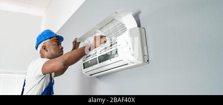 Glückliche junge afrikanische Mann Techniker Reparatur der Klimaanlage Stockfoto