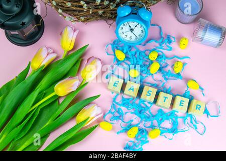 Wort Ostern auf Holzwürfeln und umgeben mit mehreren Eierdekorationen als festliche Oster-Hintergrundkomposition Stockfoto