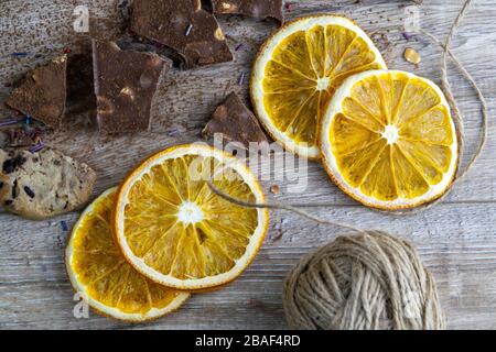 Getrocknete Orangen, Schokoladenscheiben, Schokoladengebäcke und Zimt auf einem Holztisch Stockfoto