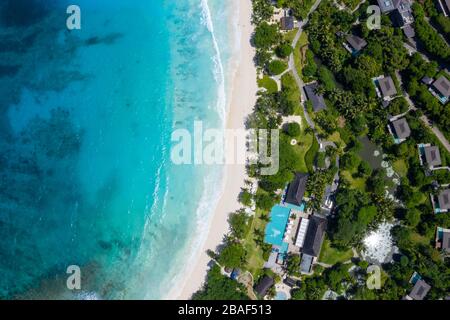 Aus der Vogelperspektive auf das Strandresort mit türkisfarbener Bucht und dichtem tropischen Wald, Anse Petite, Mahe Island, Seychellen Stockfoto