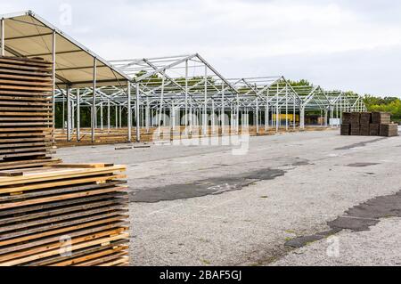 Standbau einer regionalen Messe, Zeltkonstruktion, Holzpfosten und Holzbretter für den Zeltboden auf dem Stapel, Zelte im Hintergrund, Alu Stockfoto