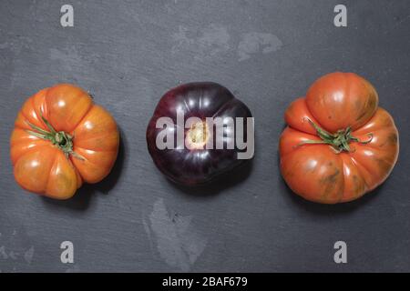 Vielfalt an rohen Tomaten auf dunklem Hintergrund Stockfoto
