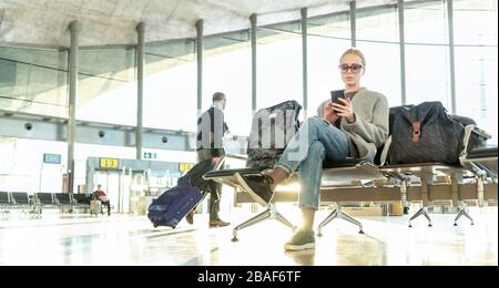 Die Frau, die über die Stornierung des Flugs am Flughafenterminal gestickt wurde, schreibt Nachricht an die Familie und sitzt wegen Coronavirus in einem fast leeren Flughafenterminal Stockfoto