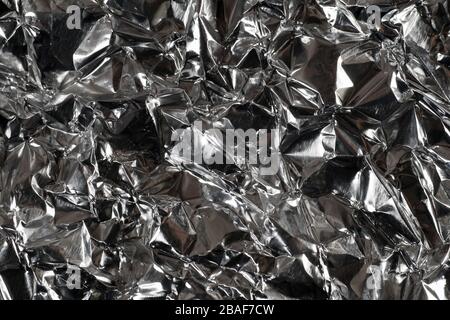 Struktur. Effektiver, kontrastierender Hintergrund aus knitterter Aluminiumfolie. Stockfoto