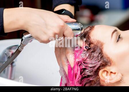 Friseursalon waschen rosa gefärbte Haare der Frau in der Spüle in der Nähe. Stockfoto