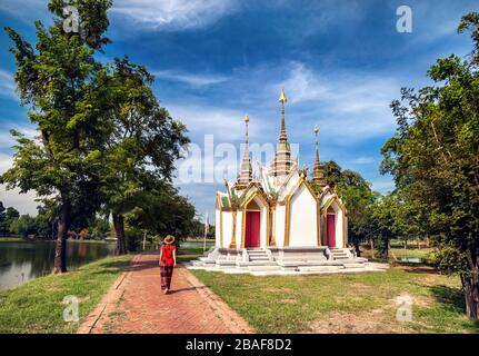 Tourist-Frau im roten T-shirt und Hut zu Fuß in der Nähe von Tempel in Südostasien Stockfoto