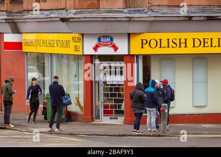 Clydebank, Großbritannien. März 2020. Kunden stehen außerhalb eines lokalen Shops, während sie warten, nacheinander eingelassen zu werden, wobei einige die soziale Distanzierung respektieren. Kredit: Colin Poultney/Alamy Live News Stockfoto