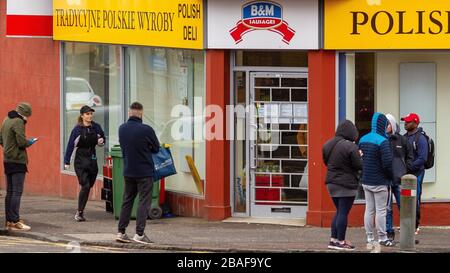 Clydebank, Großbritannien. März 2020. Kunden stehen außerhalb eines lokalen Shops, während sie warten, nacheinander eingelassen zu werden, wobei einige die soziale Distanzierung respektieren. Kredit: Colin Poultney/Alamy Live News Stockfoto