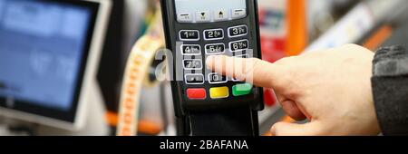 Männliche Hand, die PIN-Code-Karte eingibt, während sie an der Kasse des Supermarktes bezahlt wird Stockfoto