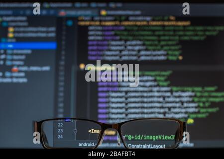 Blick durch die Brille auf den Entwicklerbildschirm mit PHP-Code, Notizbuch Stockfoto