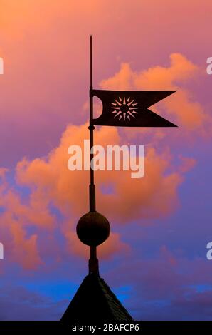 Flügelfahne auf dem Dach auf dem Hintergrund des Sonnenuntergangs Stockfoto