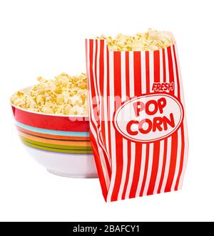 Quadratischer Schuss aus einer Schale Popcorn mit einem Beutel Popcorn, der sich daran anlehnt. Weißer Hintergrund. Etwas Kopierspeicher. Stockfoto