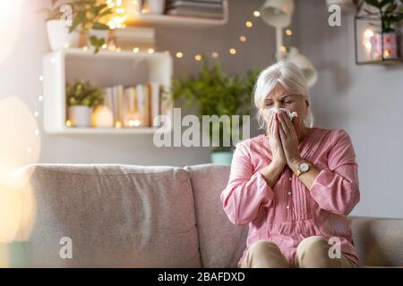 Ältere Frau, die ihre Nase weht Stockfoto