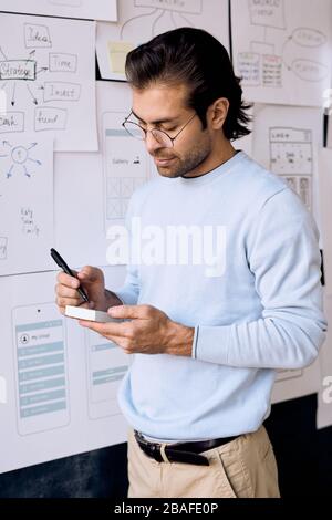 Inhalt einige Manager mittleren Alters des UI-Designunternehmens schreiben Ideen auf Haftnotizen im Büro auf Stockfoto
