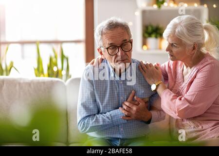 Seniorin tröstet ihren Mann zu Hause Stockfoto
