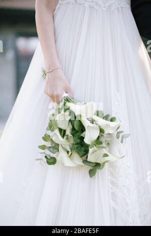 Die Frau posiert, sie zeigt sich zurück. Während die Sonne untergeht, am Hochzeitsort. Die Frau hält eine brautblume in der Hand. Stockfoto