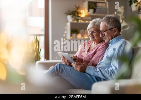 Ein reifes Paar, das einen Laptop verwendet und sich zu Hause entspannt Stockfoto