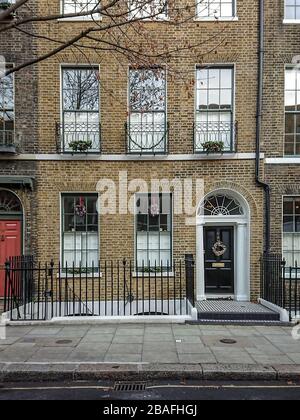 Georgian Town House, London, Großbritannien. Die Fassade zu einem typischen Reihenhaus in Central London, das mit Weihnachtskränzen und Girlanden dekoriert ist. Stockfoto