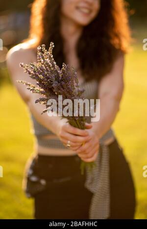 Junge Frau hält ein Bündel Lavendel in einem Feld Stockfoto