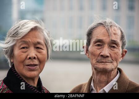 Shanghai, China - 4. Mai 2010: Nahaufnahme von Gesichtern eines älteren Ehepaares, grauender Mann und Frau, mit dunklerer Kleidung um Hälse. Stockfoto