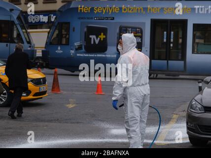 Ein Mann in Schutzausrüstung und mit einer Maske und einer Reinigung desinfizieren die Straßen in istanbul gegen das Coronavirus. Stockfoto