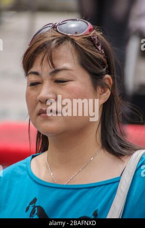 Shanghai, China - 4. Mai 2010: Nahaufnahme des Gesichts der Frau mit einer Brille im braunen Haar und mit einem blauen Hemd. Stockfoto