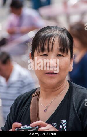 Shanghai, China - 4. Mai 2010: Nahaufnahme des Gesichts der Frau mit schwarzer Kleidung und Samsung Kamera in ihren Händen. Stockfoto