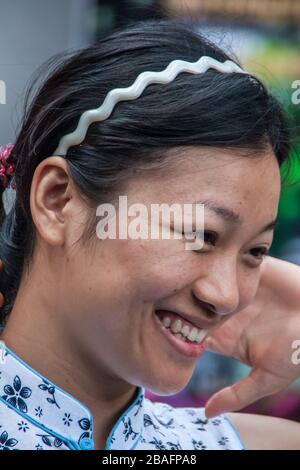 Shanghai, China - 4. Mai 2010: Portrait Nahaufnahme des Gesichts lächelnder Frau mit langem schwarzem Haar und weißem Stirnband. Stockfoto