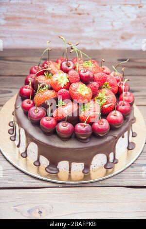 Käsekuchen mit geschmolzener Schokolade und frischen Beeren, Erdbeeren, Kirschen, Himbeeren. Stockfoto
