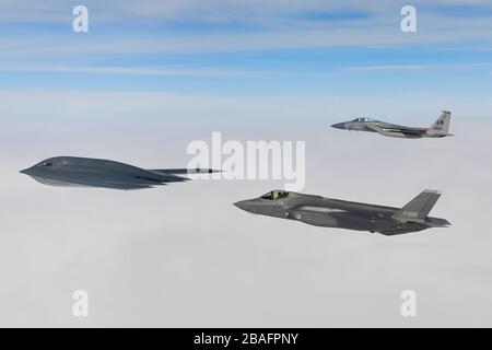 Ein Kampfflugzeug der Royal Netherlands Air Force F-35A Stealth-Kampfflugzeug und ein Kampfflugzeug der U.S. Air Force F-15C Eagle fliegen in Formation und eskortieren einen B-2A Spirit Bomber, der dem 509th Bomb Wing zugeordnet ist, während Luftoperationen zur Unterstützung der Bomber Task Force Europe 20./2. März 2020 über der Nordsee. Stockfoto