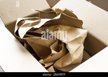 Leere Kartonverpackung brauner Papierkarton mit Deckel geöffnet, darin auf Kraftpapier verpackt Stockfoto