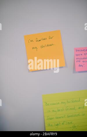 Eine orangefarbene Post-it Notiz an einer weißen Wand mit handgeschriebenem Text, der lautet: "Ich bin furchtlos für meine Kinder." Stockfoto