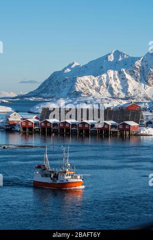 Ein Fischerboot fährt vor den Fischerhäuschen am Svinoeya Rorbuer (Hotel) in Svolvaer, einer Fischerstadt auf den Lofoten Inseln, Nordlan Stockfoto