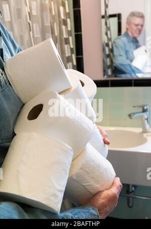 Senior man hält zusätzliche Rollen Toilettenpapier während der Coronavirus-Pandemie, USA 2020 Stockfoto