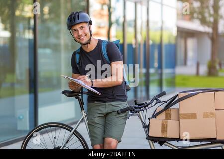 Fahrradbote, der eine Lieferung auf einem Frachtfahrrad macht Stockfoto