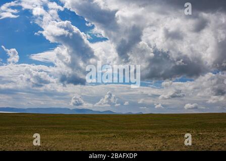 Riesige Kirgisische Steppe, in der Nähe des Songkol-Sees. Dramatischer Himmel mit epischen Wolken. Kirgisistan. Stockfoto