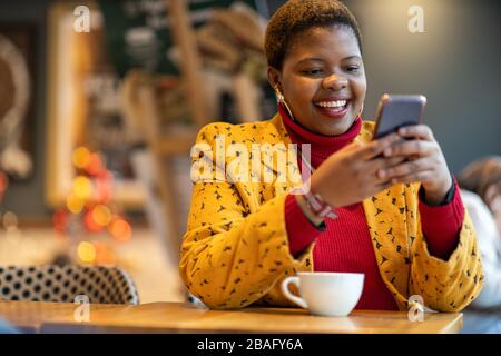 Fröhliche junge Frau mit Smartphone in einem Café Stockfoto
