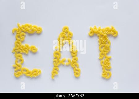 Wortessen. Italienisches Lebensmittelkonzept und Menüdesign. Ungekochte Pasta auf weißem Hintergrund. Flaches Lay. Draufsicht. Stockfoto